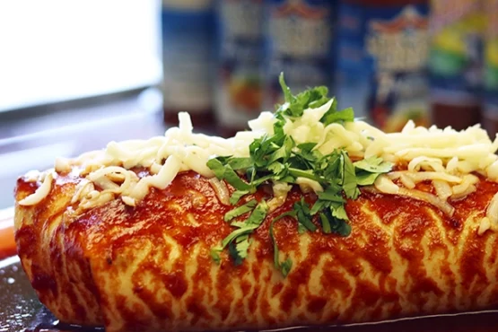 Plate with red burrito, cheese and sour cream